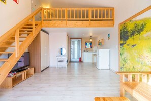 Un amplio espacio de sala con escalera de madera, cocina y comedor.