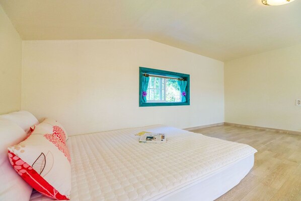 A bedroom with a bed, a window with curtains, and a light fixture on the ceiling. - Goseong Sunshine Home Pension (Goseong)