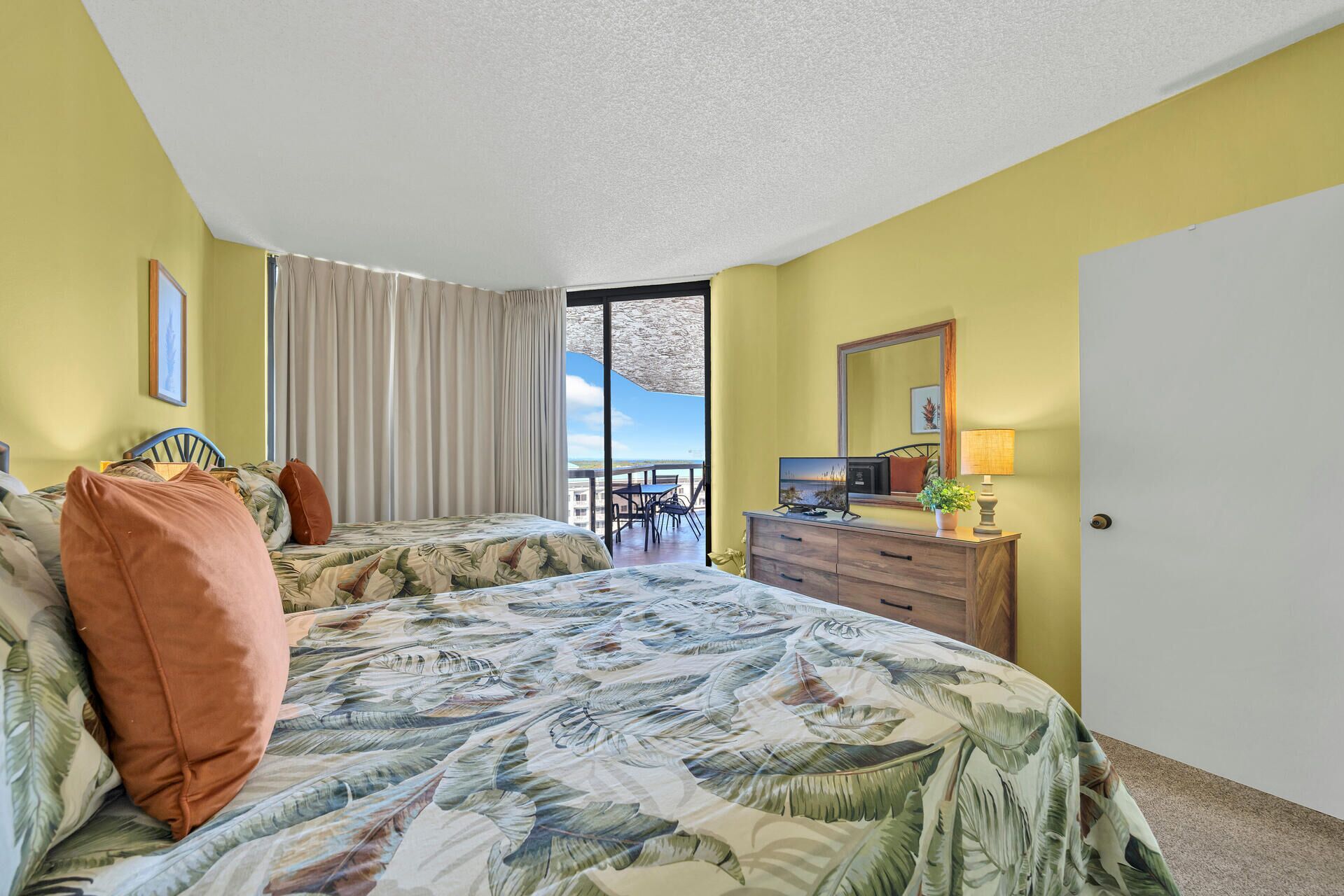 A hotel room with two beds, a large window with a view, a dresser, and a television.