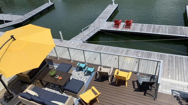 A wooden deck with outdoor furniture, including a sofa and chairs, and a yellow umbrella.
