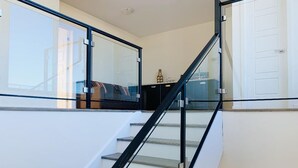 A staircase with glass railings and a white wall.