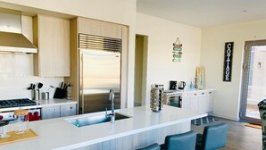 A modern kitchen with a central island, bar stools, and a coffee station.