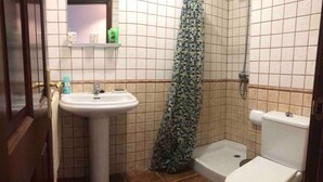 Une petite salle de bain avec un lavabo blanc, des toilettes et un rideau de douche.