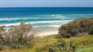 A coastal landscape with a beach, ocean, and dense vegetation. - Beachfront Hideaway (Sunrise Beach)
