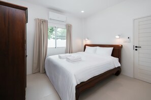 Une chambre d’hôtel avec un lit, des rideaux, un appareil de climatisation, une fenêtre et une porte.