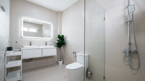 A modern bathroom with a glass shower enclosure, a white sink, and a toilet.