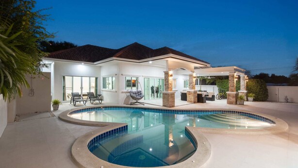A modern house with a large swimming pool and outdoor seating area.