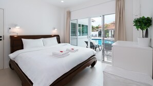 A hotel room with a bed, a desk, a chair, a window, and a view of a swimming pool.