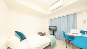 A hotel room with a bed, a desk, a chair, a television, and an air conditioning unit. - IBASHO Shibuya Dogenzaka 903 (Tokyo)