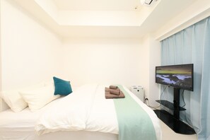 Una habitación de hotel con cama, televisor de pantalla plana y ventana con cortinas.