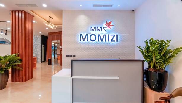 A reception desk with a logo, a potted plant, and a modern interior design.