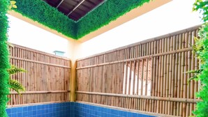 A swimming pool with bamboo walls and blue tiles.