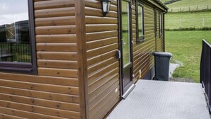Eine Holzhütte mit großen Fenstern, einer Tür und einer kleinen Veranda.