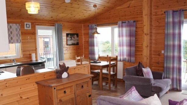 Ein gemütliches Blockhaus-Interieur mit einer Holzesstge, einer Couch und einer Küche mit Spüle und Arbeitsfläche.