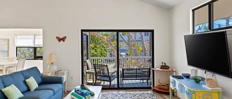 Una sala de estar con sofá, mesa de centro y vistas al balcón exterior a través de un ventanal corredero.