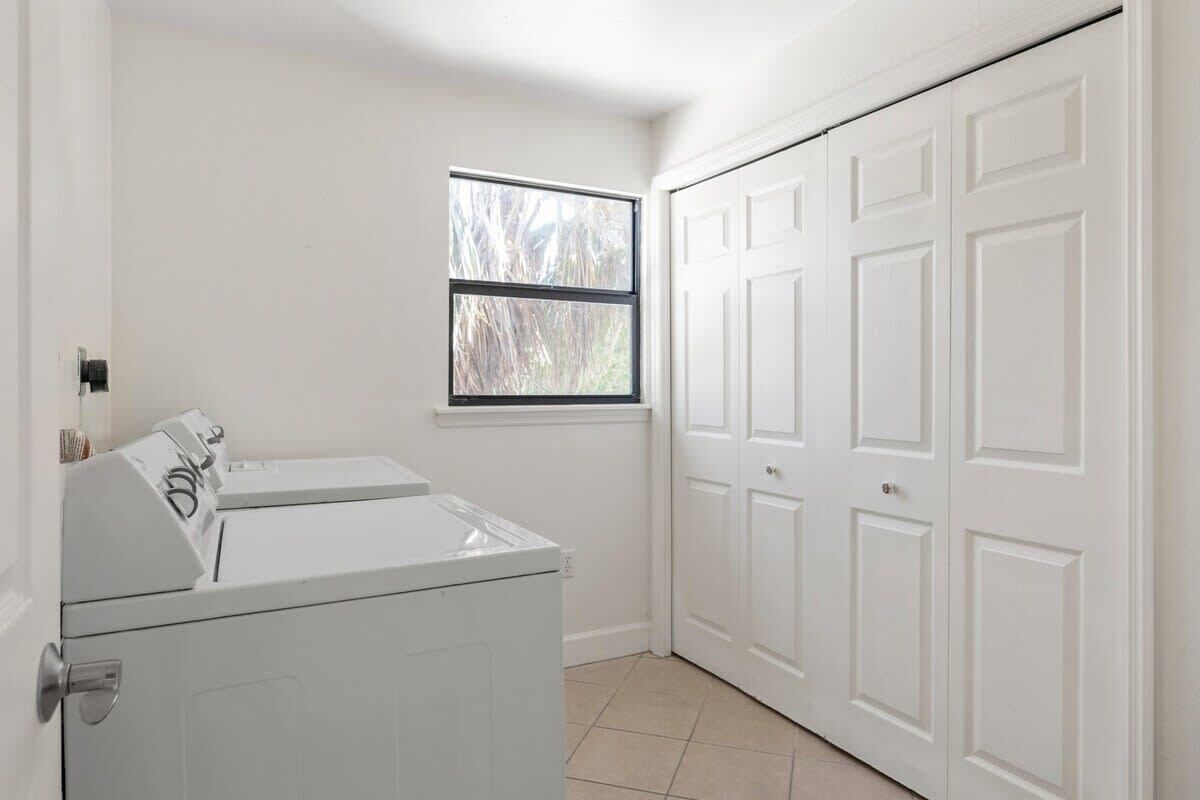 A laundry room with a washer and dryer, a window, and a white door.