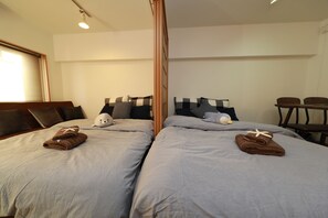 A hotel room with two beds, each with a pillow and a towel. - IBASHO Shibuya Higashi 604 (Tokyo)