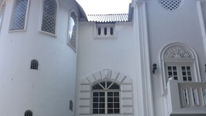 Ein weißes Gebäude mit einem zentralen Eingang, Rundbogenfenstern und dekorativen Elementen.