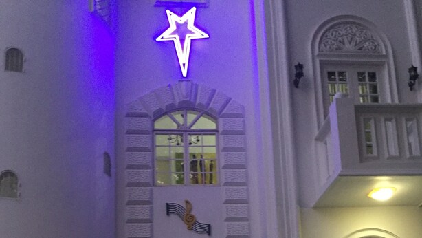Ein Gebäudeeingang mit Sternzeichen, einer Glocke und einer Weihnachtsmann-Dekoration.