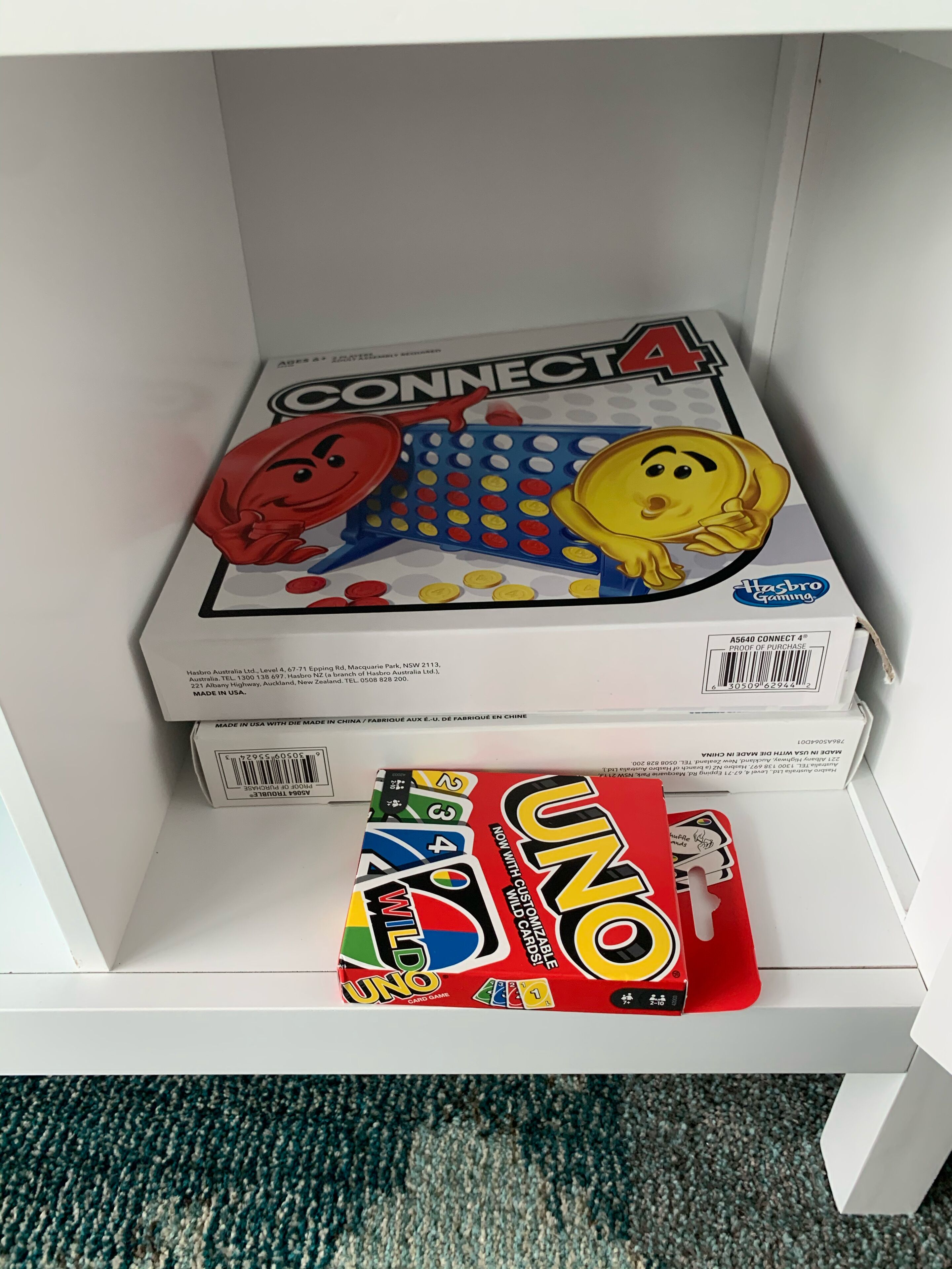 A white shelf with a Connect4 game box and a Uno game box.
