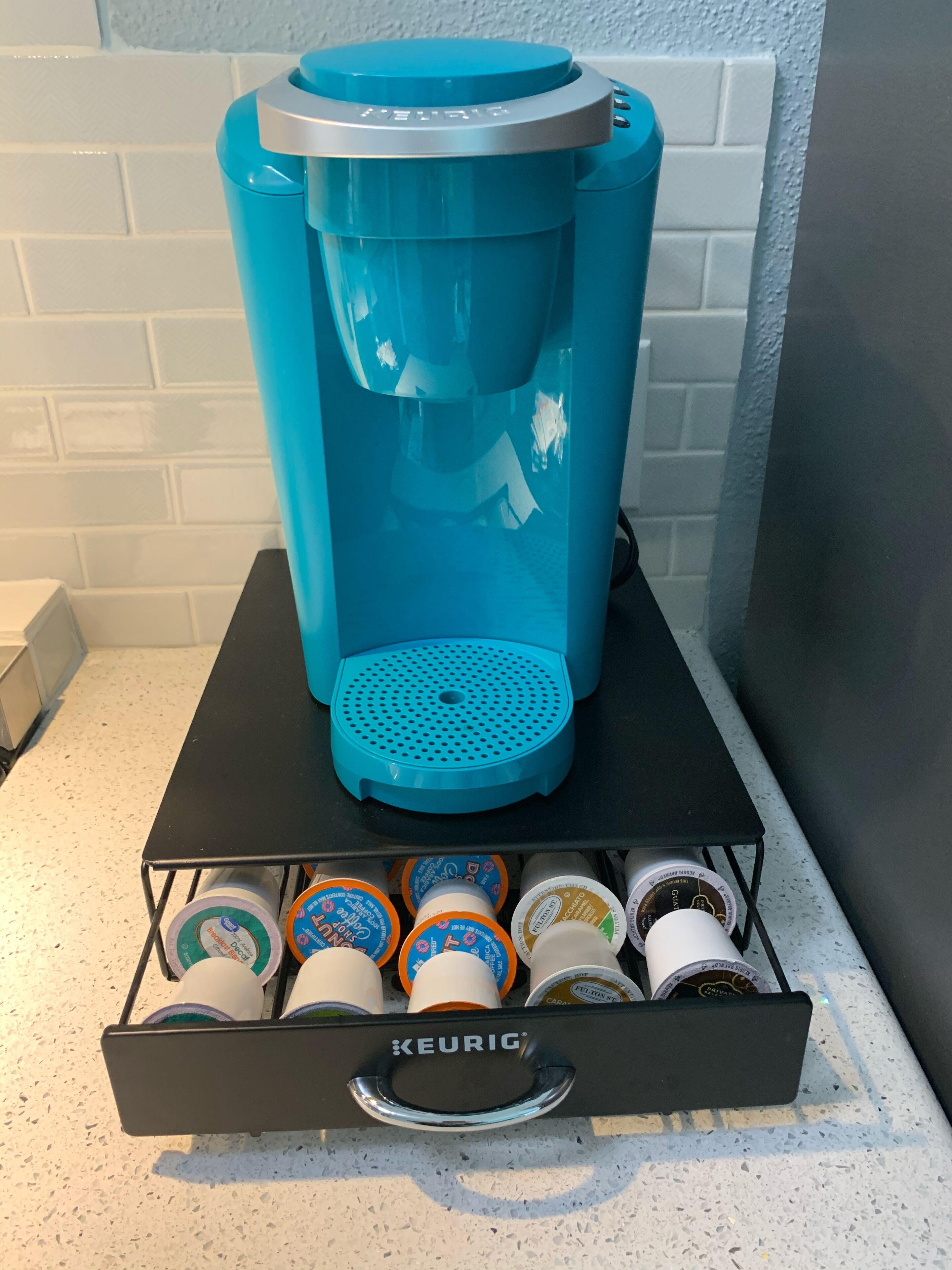 Keurig-kahvinkeitin, jonka alla on kahvikapseliteline.