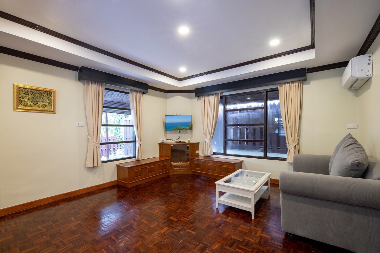 A living room with a wooden floor, a grey sofa, a coffee table, and a TV.