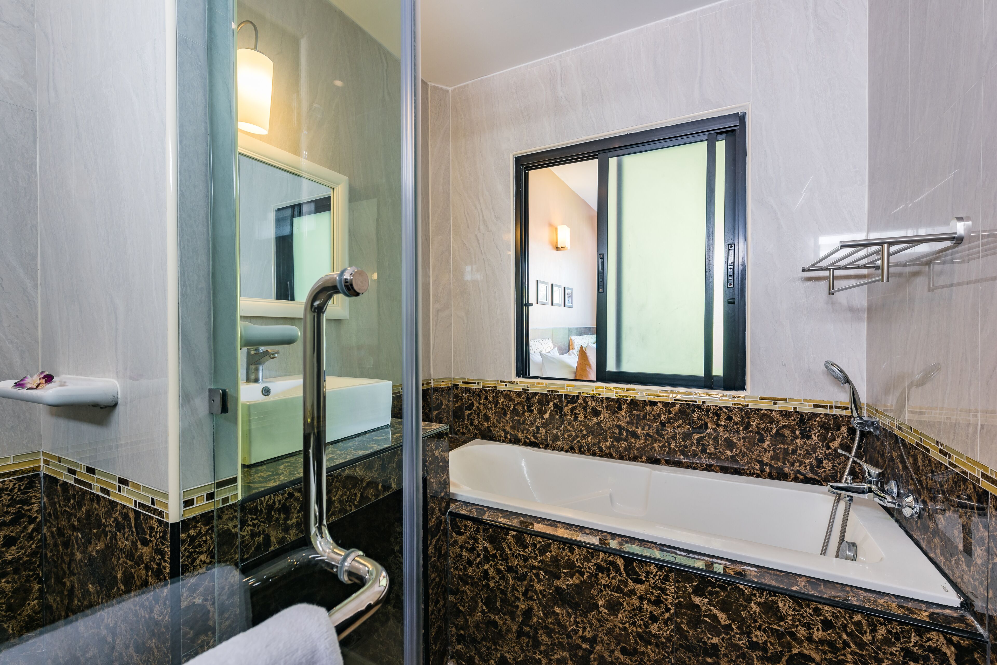Un baño moderno con una bañera grande, mampara de ducha de vidrio y tocador con espejo.