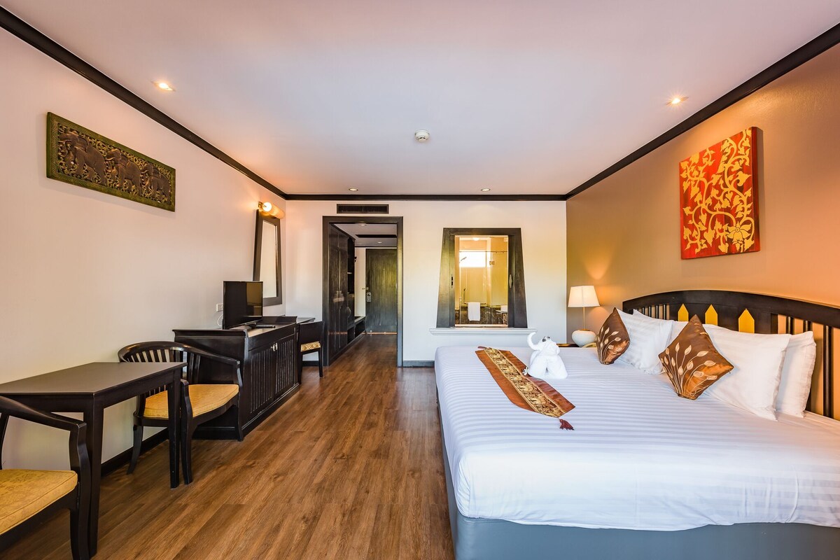 Habitación de hotel con cama, escritorio, sillas y espejo.