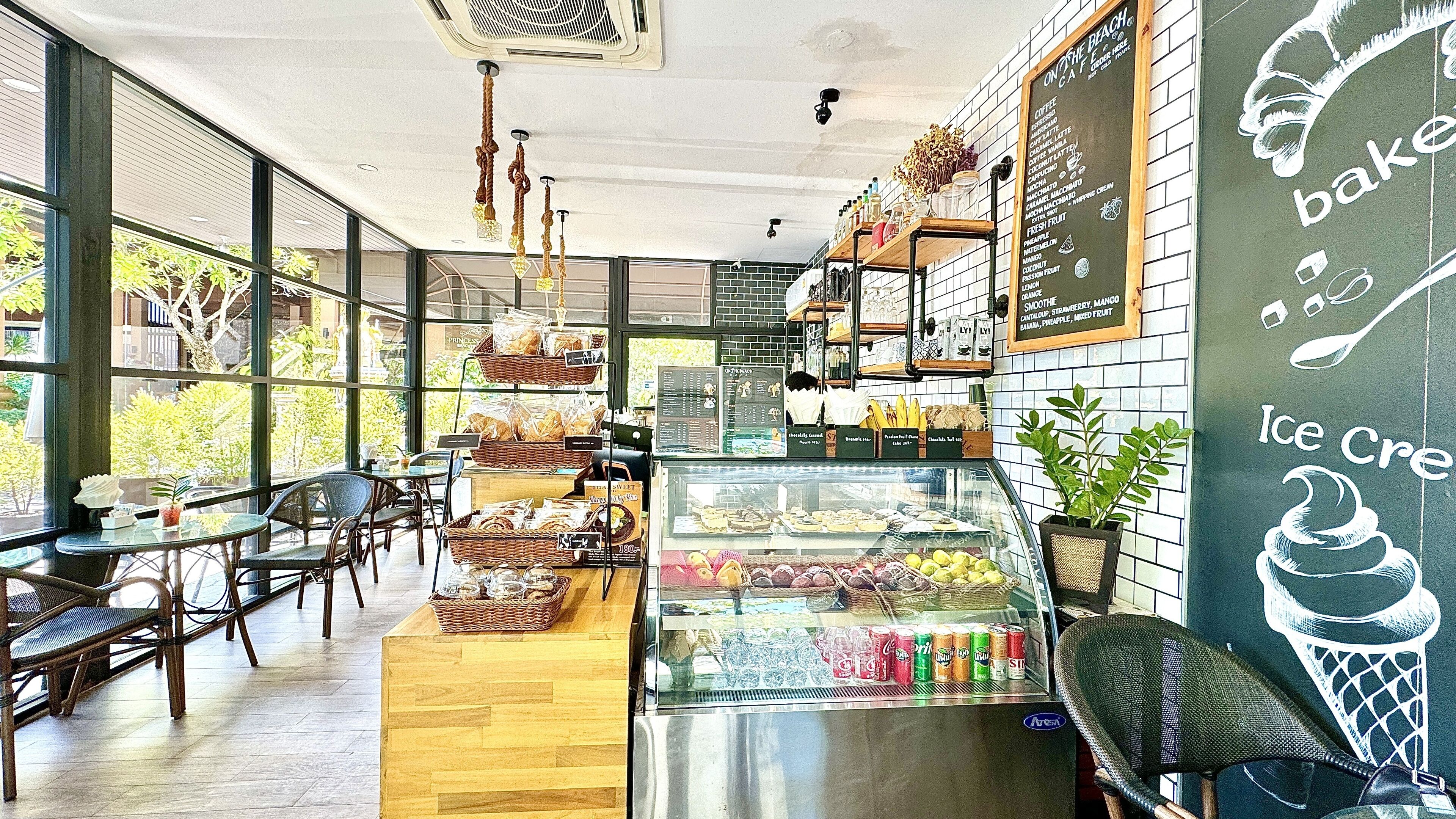 A café interior with a bakery display, seating area, and a menu board.