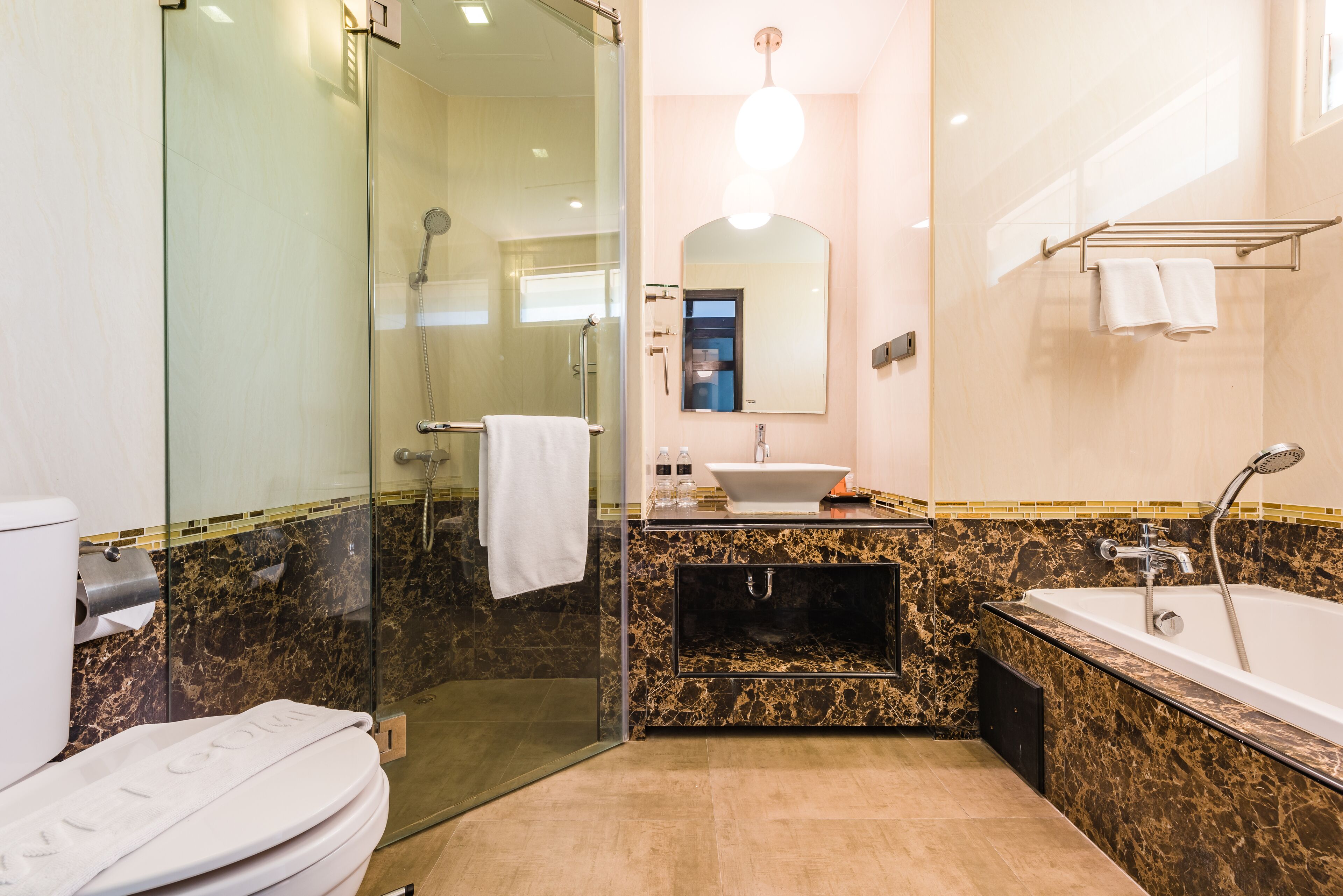 Une salle de bain moderne dotée d’une douche à parois de verre, d’un meuble-lavabo en marbre, d’un évier et d’une baignoire.