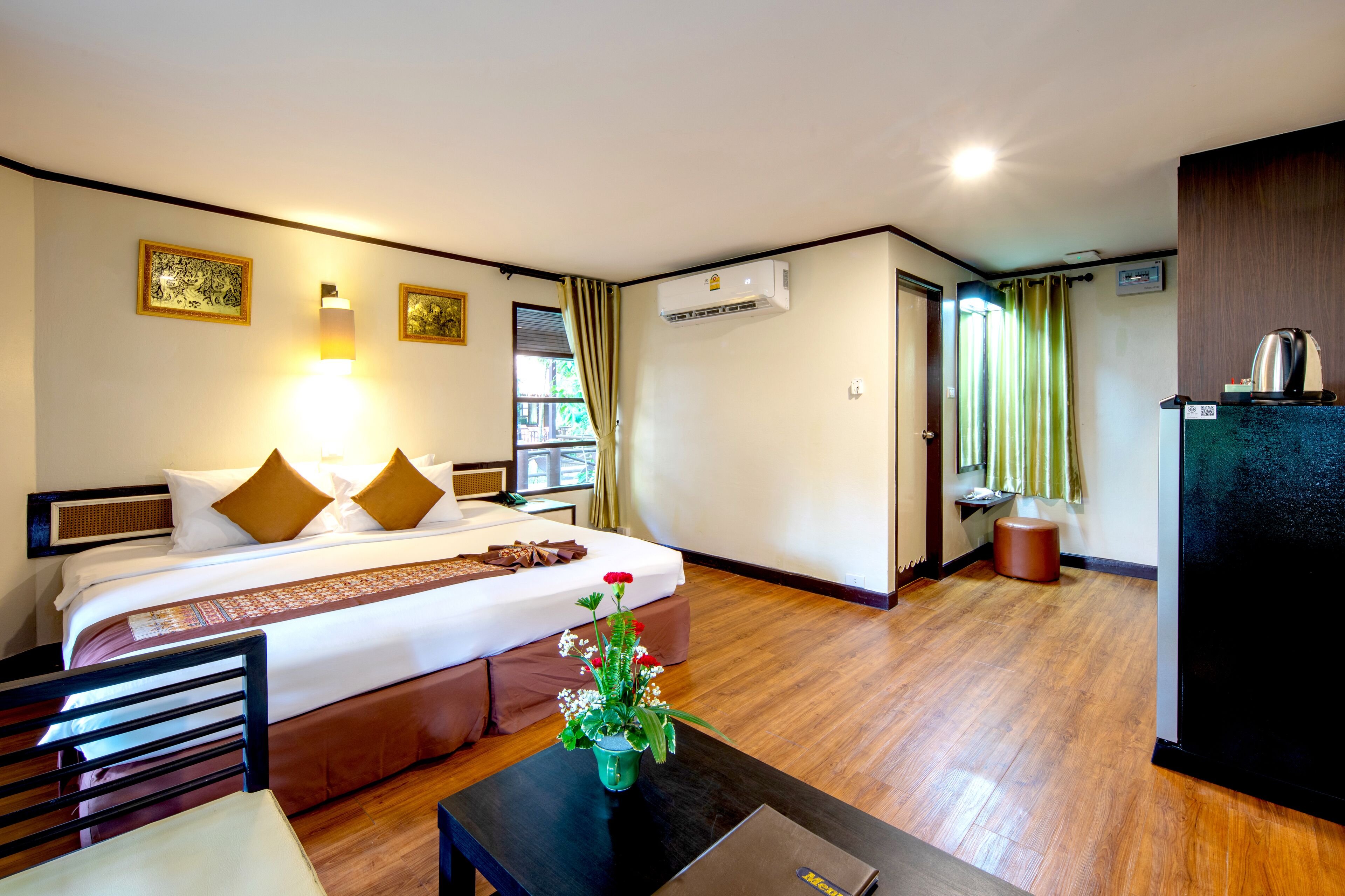 A hotel room with a bed, a desk, a chair, a coffee maker, and a plant.