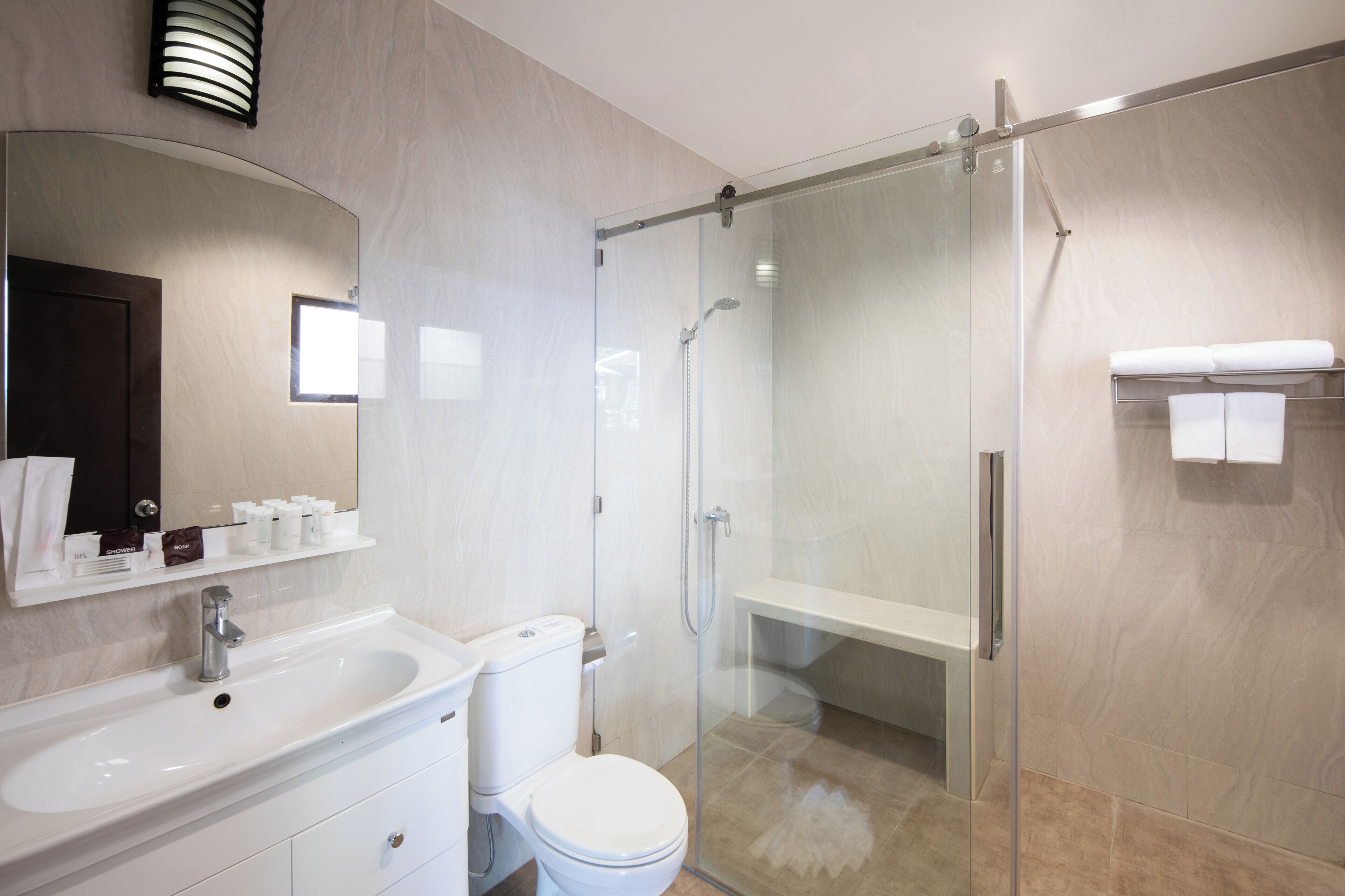 Un baño moderno con ducha de vidrio, lavamanos blanco y retrete.