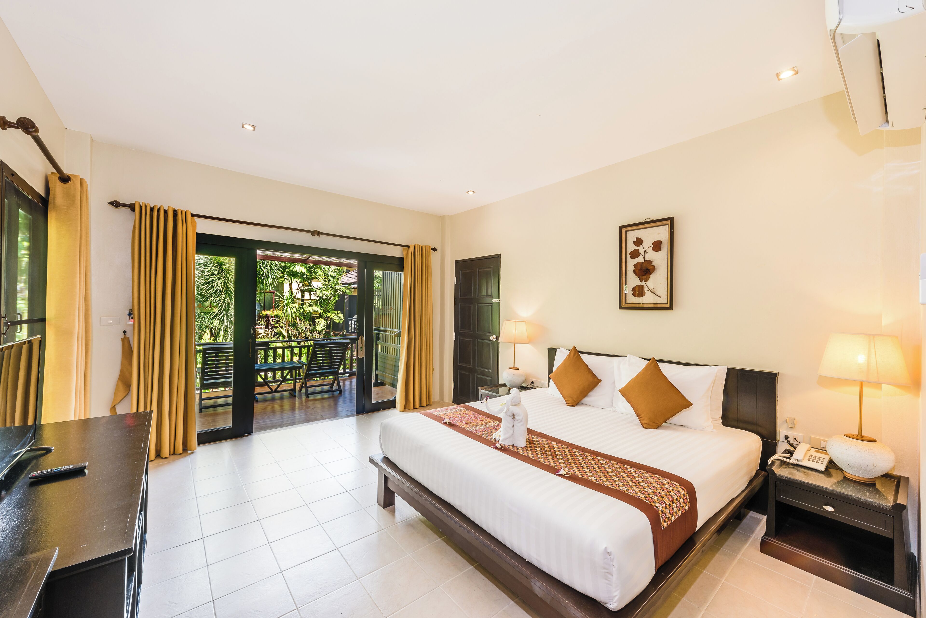 A hotel room with a bed, bedside tables, a desk, a telephone, and a view of the outdoors.