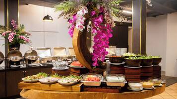 Ein reichhaltiges Buffet mit verschiedenen Speisen und einer dekorativen Blumenanordnung.