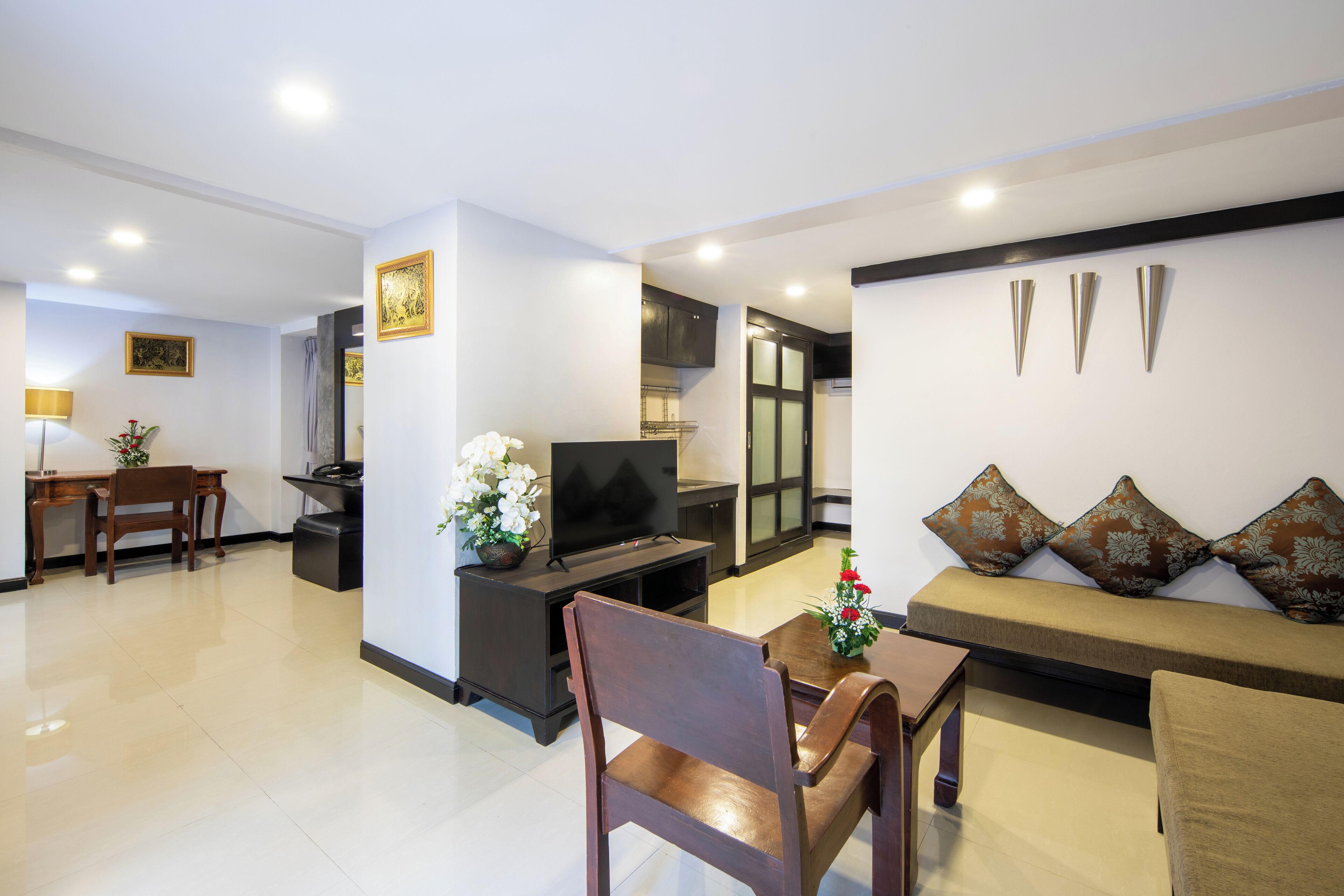 A modern living room with a sofa, a coffee table, a TV, and a dining area with a table and chairs.