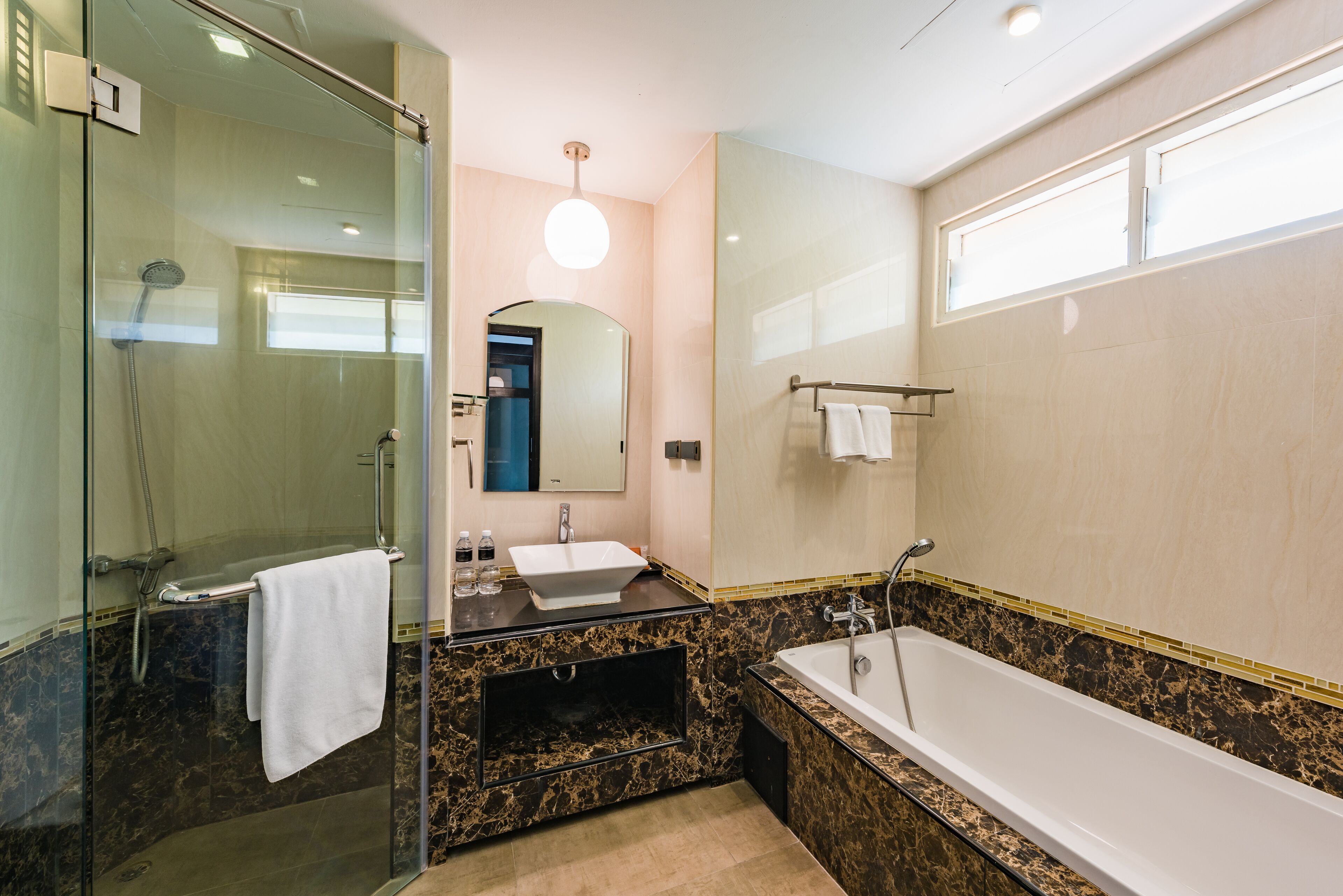 A modern bathroom with a glass-enclosed shower, a sink with a marble countertop, and a freestanding bathtub.