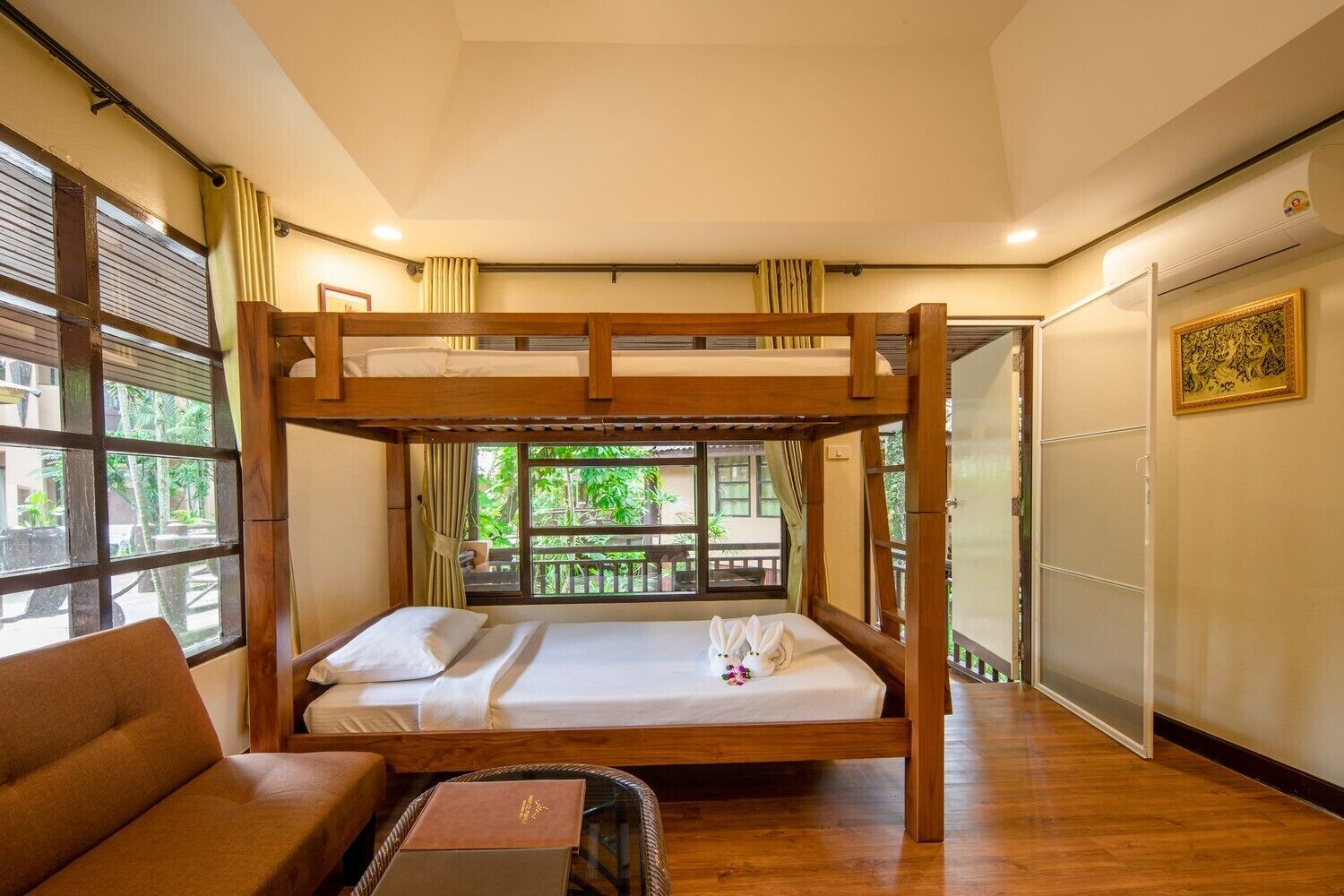 A bunk bed room with a wooden frame, a single bed, a chair, and a small table.
