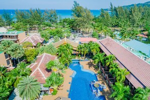 Un resort con piscina, palmeras y vista al océano.