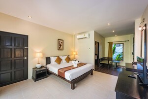 Habitación de hotel con cama, lámparas de noche, televisión y baño visible a través de una puerta abierta.