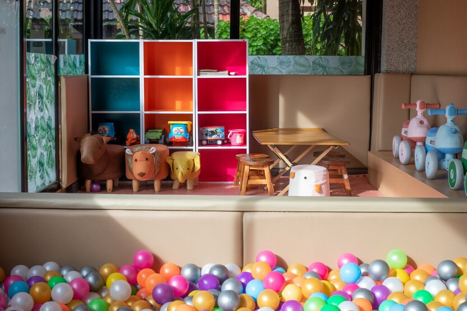 Een kinderspeelruimte met kleurrijk speelgoed, een bällebad en een boekenplank met diverse spullen.