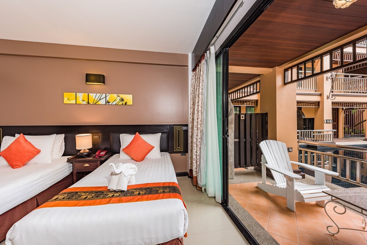 Habitación de hotel con dos camas, un balcón y vistas al exterior del edificio.