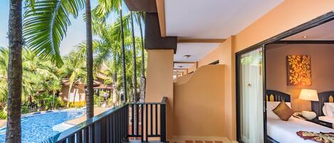 Habitación de hotel con vista a una piscina, un balcón con barandilla y una cama con almohadas y lámpara.
