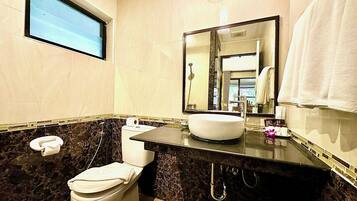 A bathroom with a marble sink, a toilet, a mirror, and a window.
