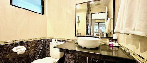 Un baño con lavamanos de mármol, inodoro, espejo y ventana.