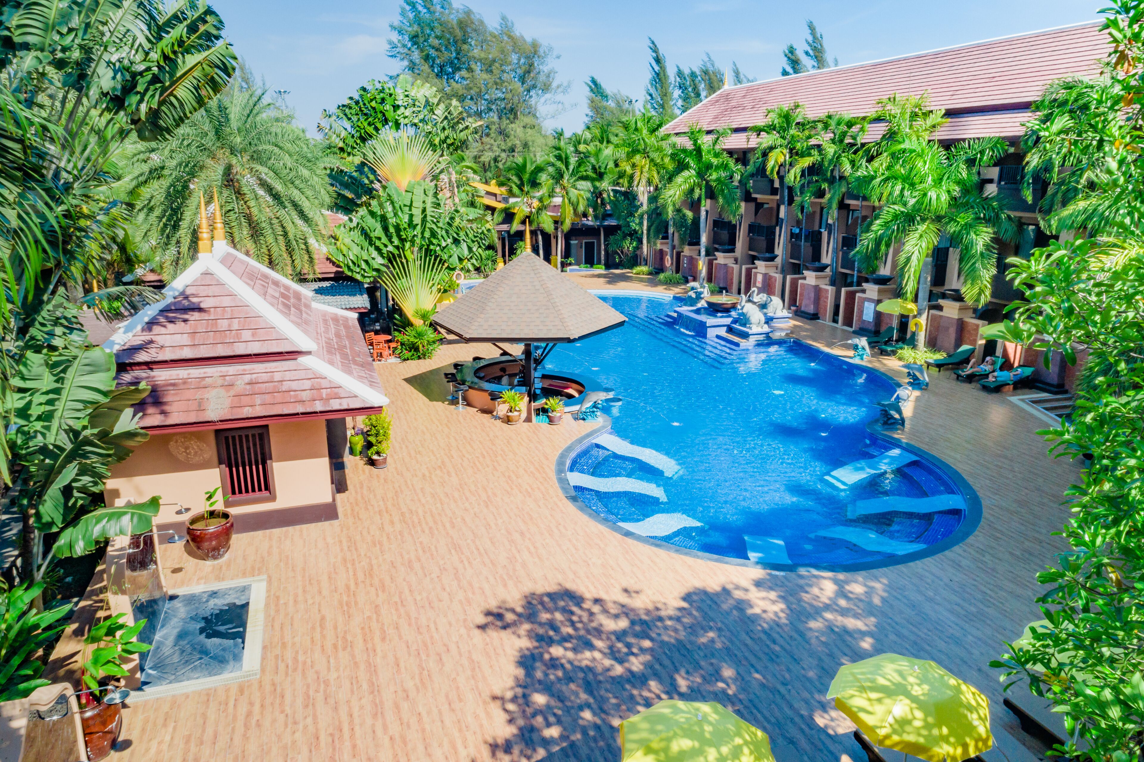 Un resort con piscina, palmeras y un área de descanso cubierta.