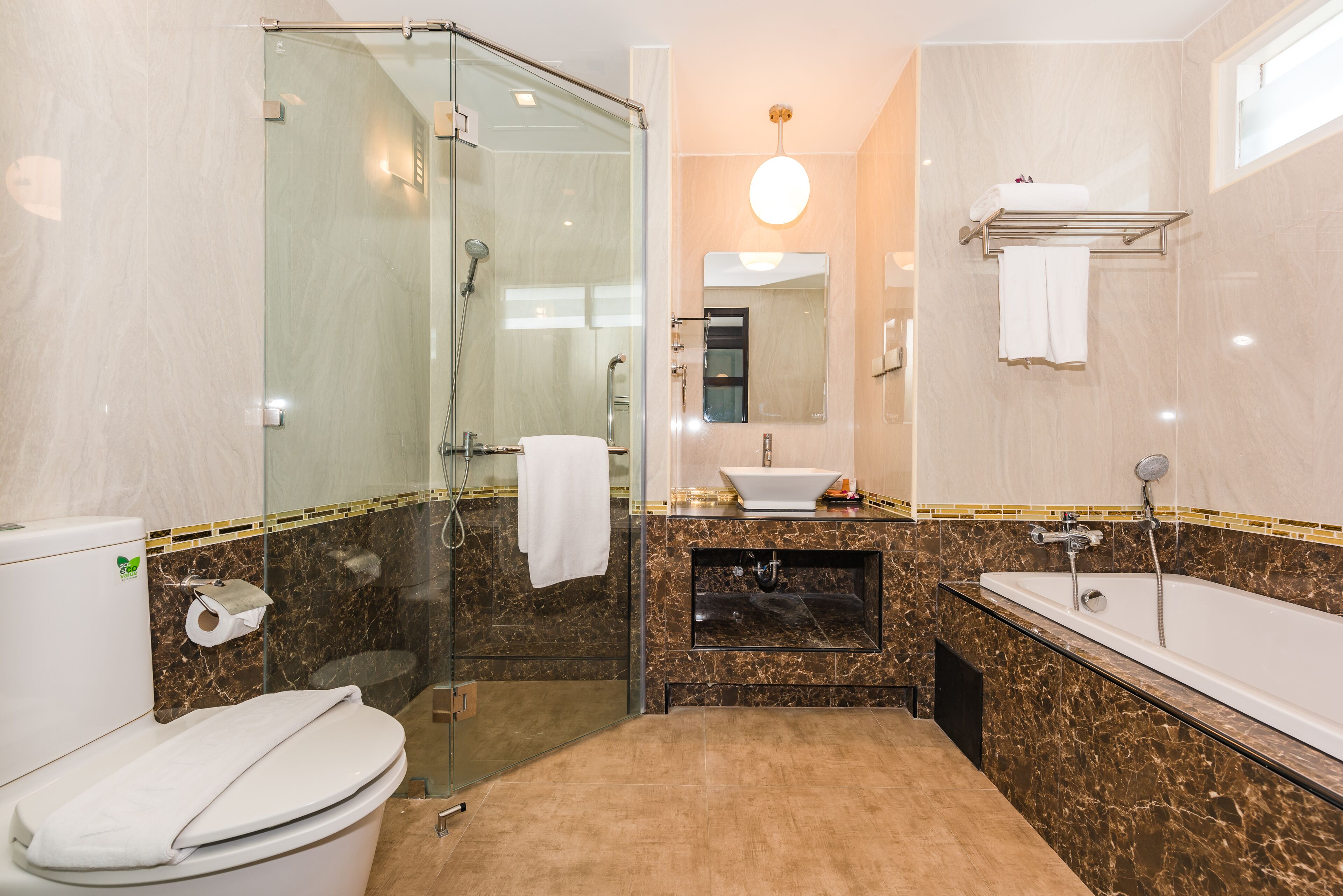 Une salle de bain dotée d’une douche à parois de verre, d’un lavabo avec un plan de travail en marbre et d’une baignoire.