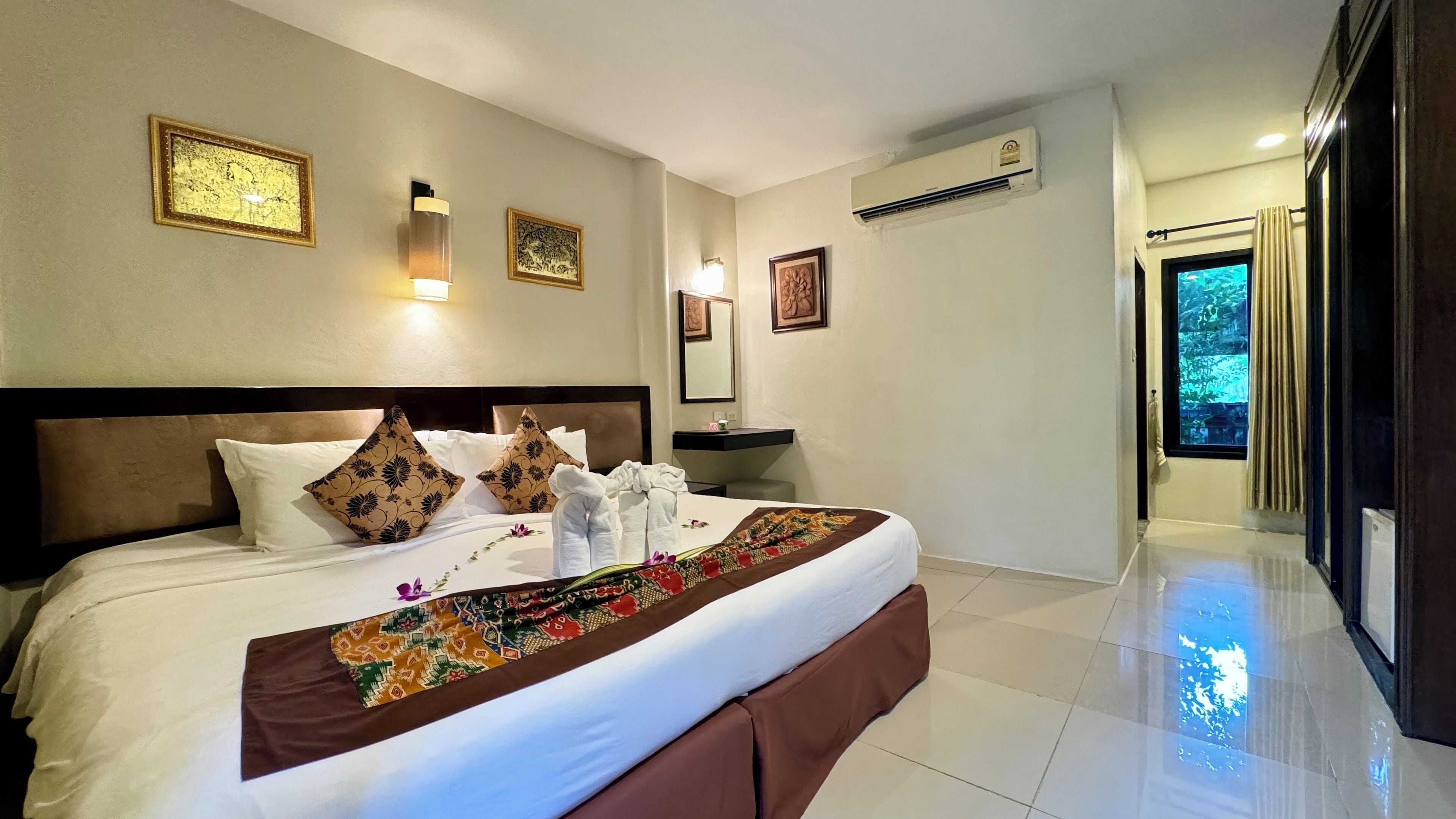 Habitación de hotel con una cama grande, una mesita de noche, aire acondicionado instalado en la pared y una ventana con cortinas.
