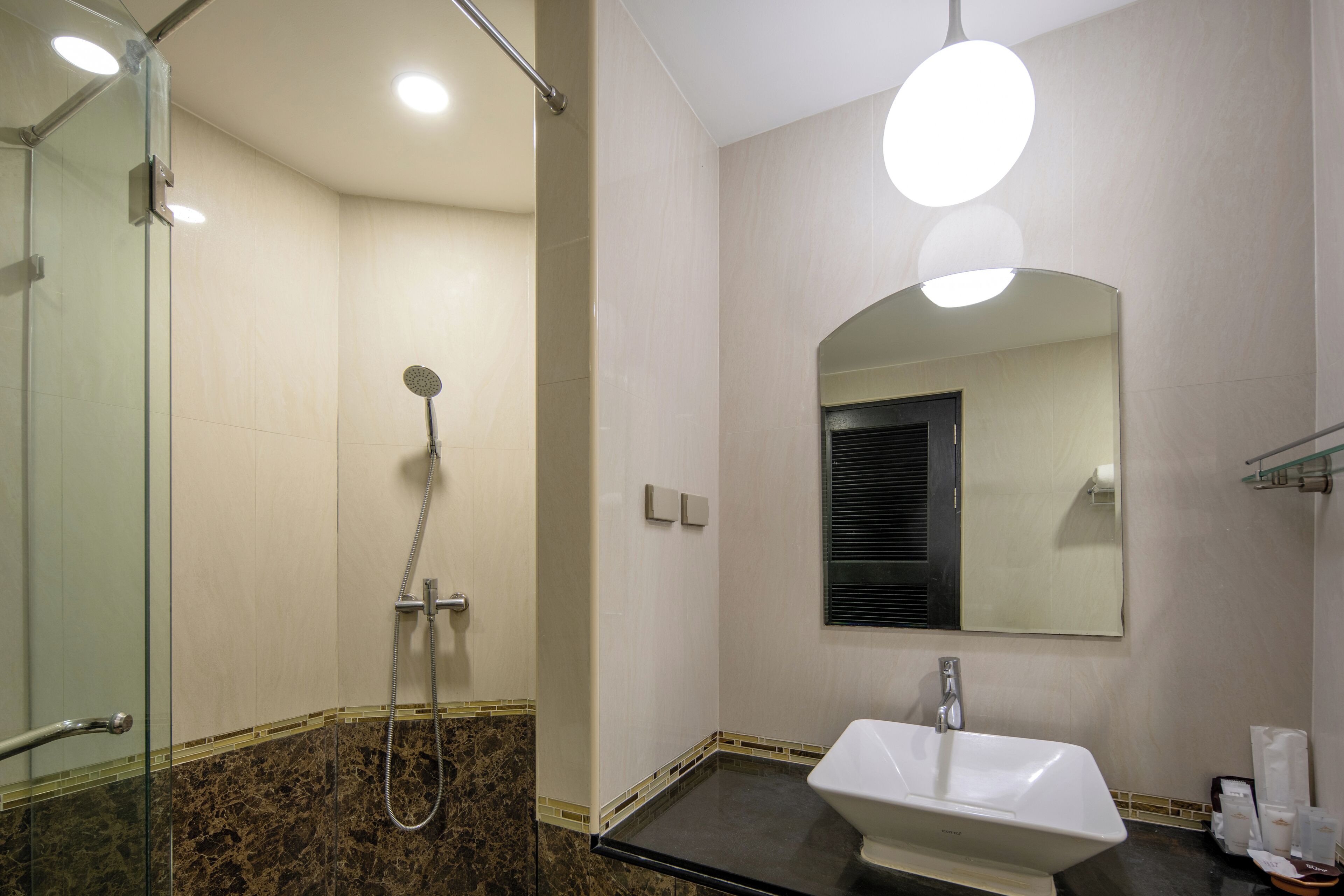 A bathroom with a glass shower enclosure, a sink with a mirror above it, and a towel rack.
