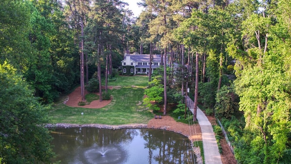 A house surrounded by a pond and dense forest.