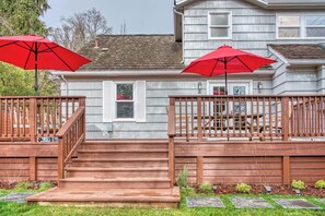 A two-story house with a wooden deck, a staircase, and two red umbrellas. - 5 Bedroom, 3 Bath House! With Brand New Hot Tub! (Eugene)